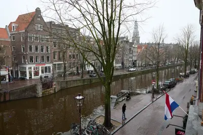 a river in a city with buildings and a man with a flag at redlight canalview city centre in Amsterdam