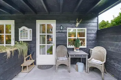 a patio with wicker chairs and a table on a house at B&B Hoofddorp in Hoofddorp