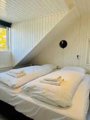 two beds in a room with white sheets and towels at Beachhouse R&M in Noordwijk aan Zee