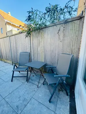 two chairs and a table in front of a fence at Beachhouse R&M in Noordwijk aan Zee