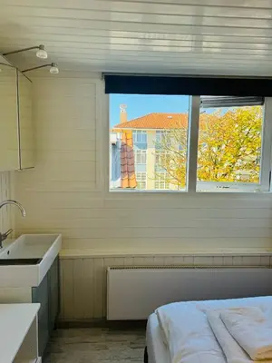 a kitchen with a window and a sink and a bed at Beachhouse R&M in Noordwijk aan Zee