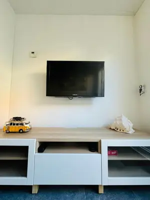 a white entertainment center with a flat screen tv on a wall at Beachhouse R&M in Noordwijk aan Zee