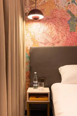 a bedroom with a bed and a table with a bottle on it at THE FRITZ Hotel Amsterdam in Amsterdam
