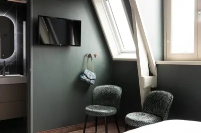 a room with three chairs and a tv on a wall at THE FRITZ Hotel Amsterdam in Amsterdam
