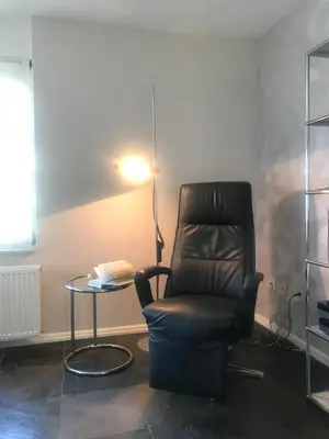 a room with a chair and a table and a lamp at Meerblick Atlantis 17 c in Egmond aan Zee