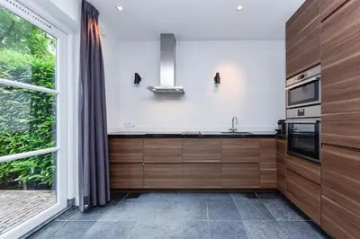 a kitchen with wooden cabinets and a large window at Luxury semi-detached house near Amsterdam in Loenen aan de Vecht