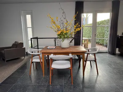 a dining room table with chairs and a vase with flowers at Luxury semi-detached house near Amsterdam in Loenen aan de Vecht