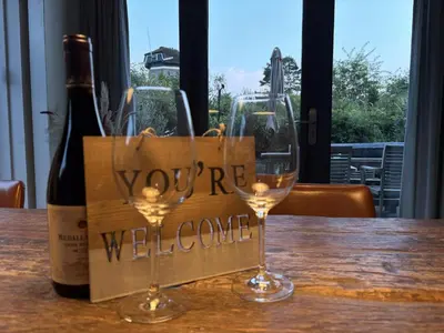 two wine glasses sitting on a table with a wine welcome sign at Villa Happy Days in Egmond aan Zee