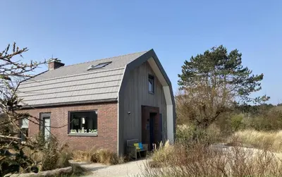 a barn conversion with a brick and gray roof at Villa Happy Days in Egmond aan Zee