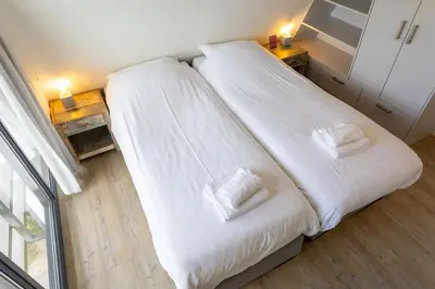 a bedroom with two beds with white sheets and towels at Villa Duinroos in Egmond aan den Hoef