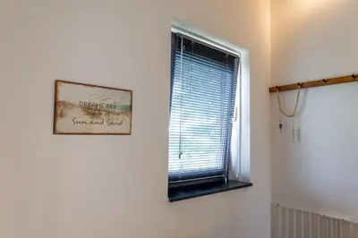 a window in a room with a picture on the wall at Villa Duinroos in Egmond aan den Hoef