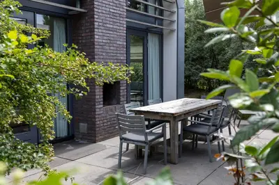 a wooden table and chairs on a patio at Villa Duinroos in Egmond aan den Hoef
