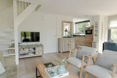 a living room with a couch and a tv at Villa Duinroos in Egmond aan den Hoef