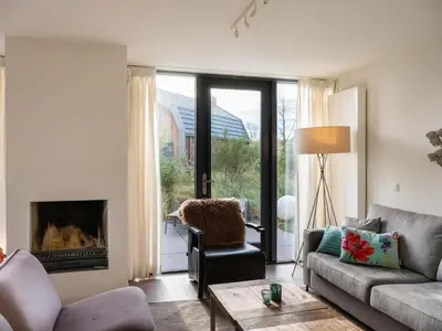 a living room with a couch and a fireplace at Villa Zeester in Egmond aan den Hoef