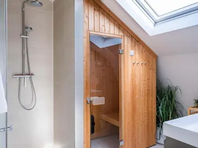 a shower in a bathroom with a wooden wall at Villa Zeester in Egmond aan den Hoef