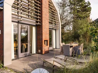 a patio with chairs and a table in front of a building at Villa Zeester in Egmond aan den Hoef