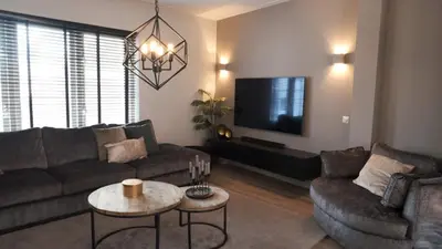 a living room with a couch and a tv at 't Sand Apartment in Zandvoort