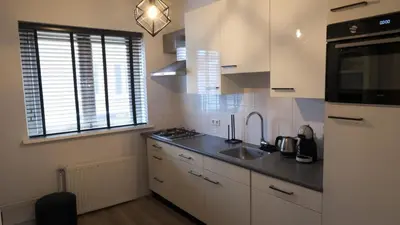 a kitchen with white cabinets and a sink at 't Sand Apartment in Zandvoort