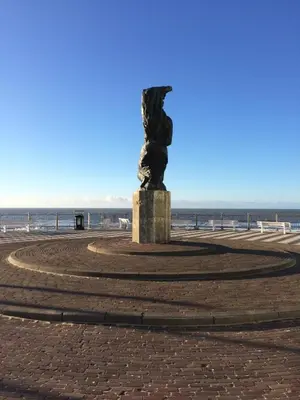 a statue on the beach with the ocean in the background at 't Sand Apartment in Zandvoort