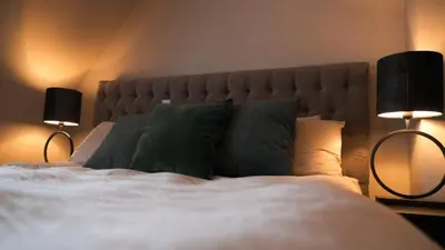 a bedroom with a bed with pillows and two lamps at 't Sand Apartment in Zandvoort