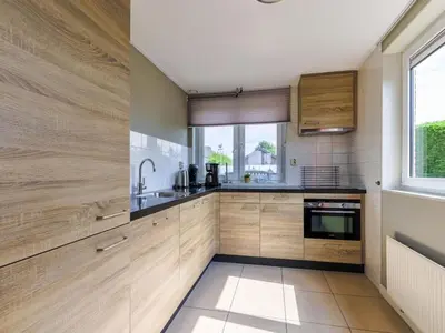 a kitchen with wooden cabinets and a window at Waterlelie Vakantiepark De Groote Vliet in Wervershoof