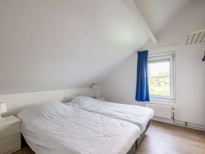 a bedroom with a white bed and a window at Waterlelie Vakantiepark De Groote Vliet in Wervershoof