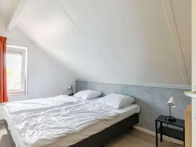 a bedroom with a white bed in a attic at Waterlelie Vakantiepark De Groote Vliet in Wervershoof