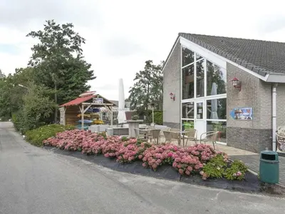 a restaurant with pink flowers in front of a building at Waterlelie Vakantiepark De Groote Vliet in Wervershoof