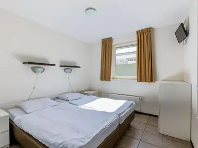 a bedroom with a bed and a window at Wilgenroos Vakantiepark De Groote Vliet in Wervershoof