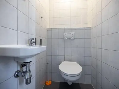 a white bathroom with a toilet and a sink at Wilgenroos Vakantiepark De Groote Vliet in Wervershoof