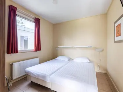 a bedroom with a white bed and a window at Wilgenroos Vakantiepark De Groote Vliet in Wervershoof