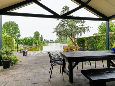 a patio with a table and chairs and a river at Bungalow in Wervershoof with 1 bedroom in Wervershoof