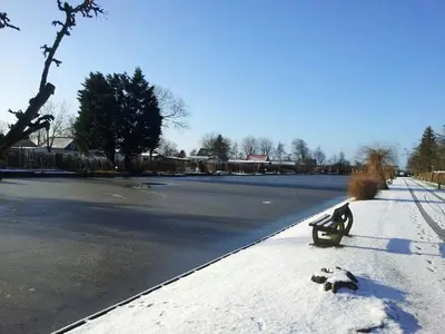 a snow covered sidewalk with a bench next to a street at Bungalow in Wervershoof with 1 bedroom in Wervershoof