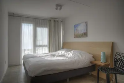 a bedroom with a bed and a chair and a window at Atlantis 14 in Egmond aan Zee