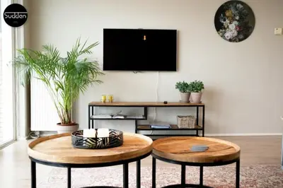 a living room with two tables and a tv on a wall at Atlantis 18 in Egmond aan Zee