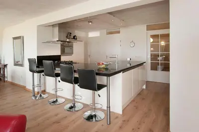 a kitchen with a counter and stools in a room at Atlantis 19a in Egmond aan Zee