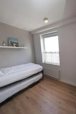 a small bedroom with a bed and a window at Atlantis 19a in Egmond aan Zee