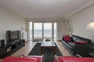 a living room with a black leather couch and a table at Atlantis 19a in Egmond aan Zee