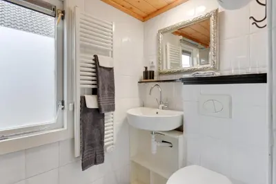 a white bathroom with a sink and a mirror at The White Cottage in Uitgeest