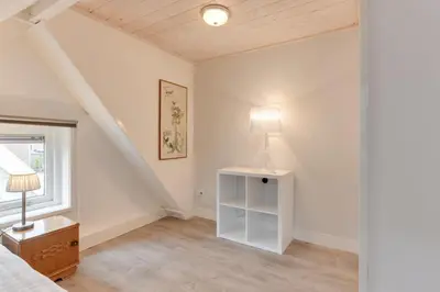 a bedroom with a bed and a lamp and a window at The White Cottage in Uitgeest