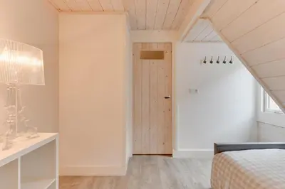 an attic bedroom with a bed and a desk at The White Cottage in Uitgeest