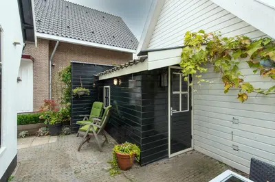a green chair sitting on the side of a house at The White Cottage in Uitgeest
