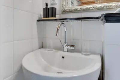 a white sink in a bathroom with a mirror at The White Cottage in Uitgeest