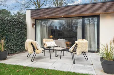 a patio with two chairs and a table in a yard at Studio Campo in Bentveld