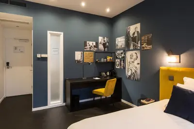 a bedroom with a desk and a bed with a yellow chair at Court Hotel Utrecht City Centre in Utrecht