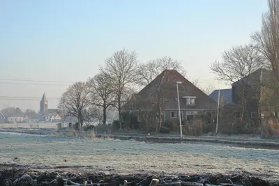 a snow covered field with houses and a church at Appartement Voorhuis en chalet Klein Waterland in Amsterdam
