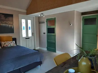 a bedroom with green doors and a bed and a table at Appartement Voorhuis en chalet Klein Waterland in Amsterdam