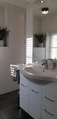 a white bathroom with a sink and a mirror at Appartement Marigold in Zandvoort