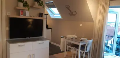 a living room with a flat screen tv and a table at Appartement Marigold in Zandvoort