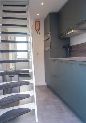a staircase in a room with a kitchen and a counter at Gestrand in Egmond aan Zee